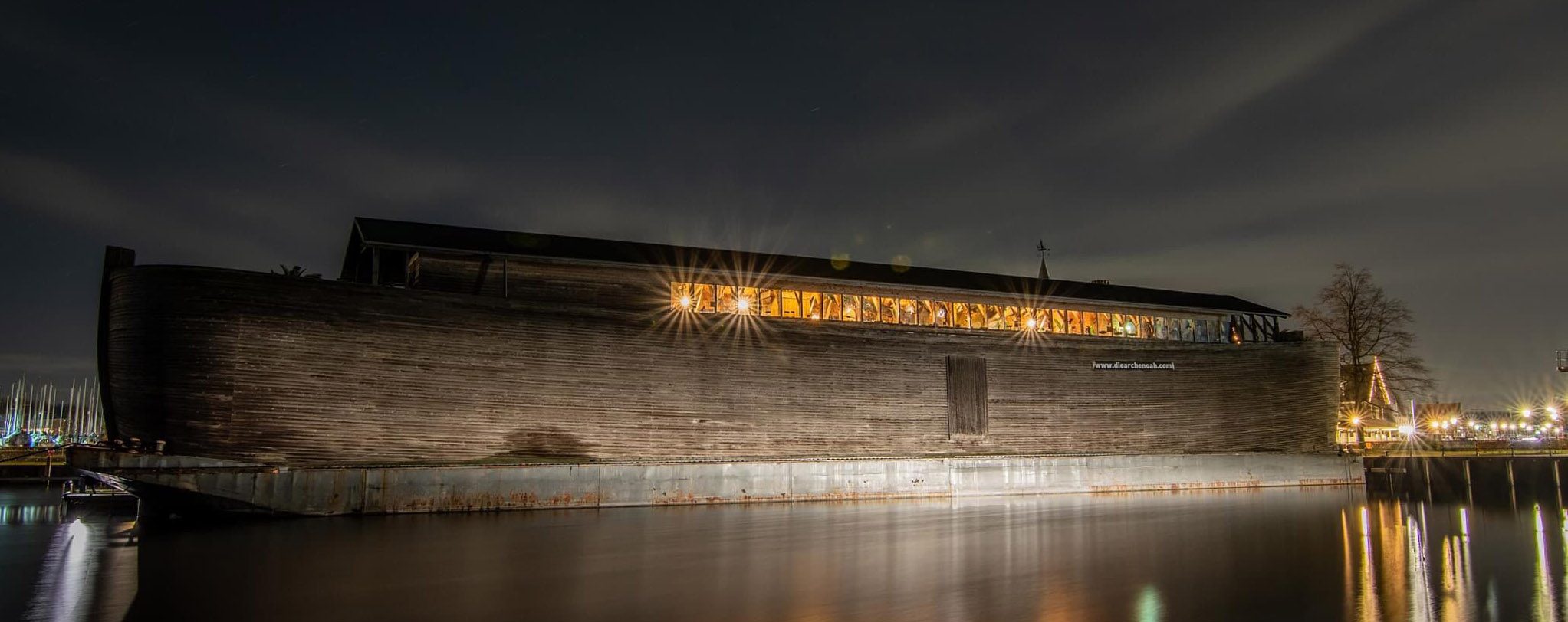 Noah’s Ark bij avond, met verlichte ramen langs de volle lengte van het schip